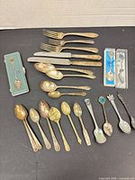 Overall layout showing forks, knives, spoons, boxed and cased souvenir spoons