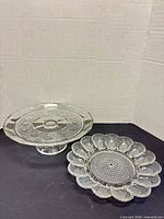 Wide shot showing both glass pieces: pedestal cake stand and deviled egg plate
