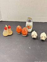 Group shot of all shakers: plastic pair in caddy, orange egg pair, Pyrex shaker, ceramic pig pair