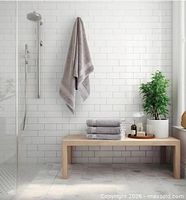 Stacked light grey towels and one hanging, showing colour and size context