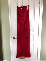 Full view of apple red strapless dress hanging on door