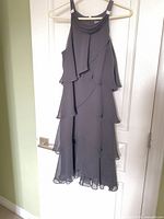Front view of black chiffon tiered Dressbarn sleeveless dress on hanger