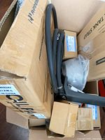 Overall view of open carton with visible hose, boxed parts and handle