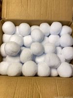 Top view of open box filled with white pom-poms
