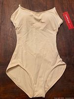 Front view of tan Capezio bodysuit with hang tag attached