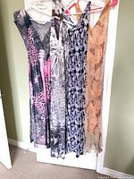 Four maxi dresses hanging on door showing overall styles and lengths