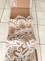 Rug partially unrolled showing tan and white pattern and woven construction