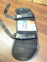 Front view of padded travel pillow showing straps, buckles and instruction leaflet