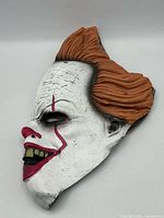 Front angled view of Pennywise mask showing orange hair and facial details