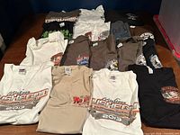 Overview of all 17 motorcycle event T-shirts laid out on table
