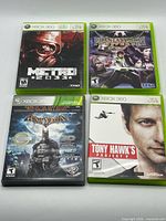 Front view of four Xbox 360 game cases: Metro 2033, Phantasy Star Universe, Batman Arkham Asylum GOTY, Tony Hawk's Project 8