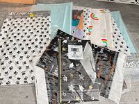 Assorted sealed table covers showing paw print design, solid blue, Encanto graphic, rainbow print, graduation print