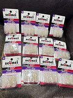 Front view of 12 Scunci packages laid out showing branding and quantity