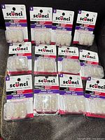 Front view of all twelve Scunci 75-count clear hair elastic packs