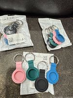 Three sealed packs containing 12 silicone AirTag holders with keyrings