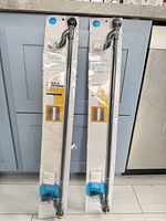 Front view of both sealed Room Essentials tension rods showing branding and length