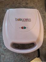 Top view of closed Babycakes cupcake maker showing logo and indicator lights