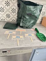 All items overview: open garden bag, three signs, shovel