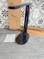 Lamp folded on base beside box and manual