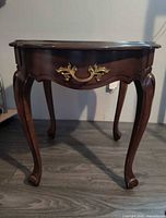 Front view showing overall table, drawer with brass pull, cabriole legs