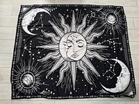 Full view of black Sun and Moon wall tapestry laid flat on floor