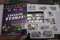 Cover of 2017 Unitrade catalogue beside assortment of Canadian stamps in sleeves