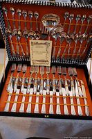 Open flatware case showing all 51 pieces and certificate