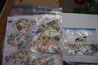 Eight clear plastic bags filled with assorted postage stamps, one labelled Mint