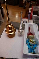 Group shot of blue tree topper in box, copper finial, silver finial