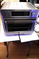 Front view of Frigidaire digital air fryer oven showing control panel, glass door and interior basket
