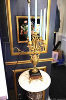 Full view of gilded five-arm candelabra with blue candles on marble plinth