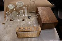 Group of glassware, bottles, flasks, test tubes in wooden rack, glass tubing and oak box