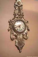 Full view of ornate gilded French wall clock on wall
