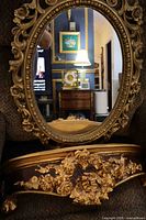 Oval ornate gold wall mirror and matching wall shelf shown together