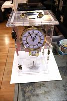 Front view of Lucite case brass clock showing dial and case