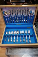 Open flatware case showing knives, forks, spoons, serving spoons