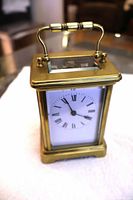 Front view of brass carriage clock showing dial and handle
