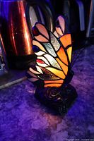 Front lit view of butterfly lamp showing stained glass colours and rose base