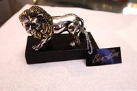 Profile view of silver lion figurine with tag