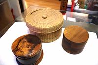 Three containers: burlwood coaster set left, straw basket back, teak box right