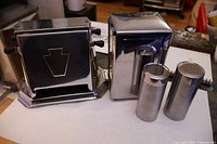 Front view of chrome toaster, napkin dispenser and cylindrical shakers