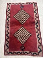 Full view of the Shiraz rug showing red field, two cream/black diamond medallions, zigzag border