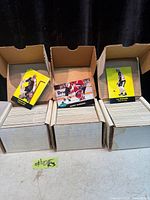 Three open cardboard boxes showing stacks of hockey cards with sample cards on top
