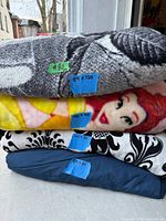 Stack of four folded blankets showing colors and textures