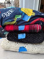 Stack of four blankets showing colours and sizes on tape