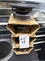 Stack of four speaker drivers in cardboard sleeves with handwritten label x4