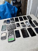 Overview of 19 assorted cell phones spread on table