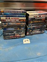 Two stacks of assorted DVDs, Blu-rays and possible 4K titles on blue surface