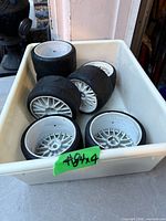 Tray containing the seven black rubber tires mounted on white rims