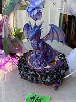 Close-up of purple dragon figurine on black stone-edged base